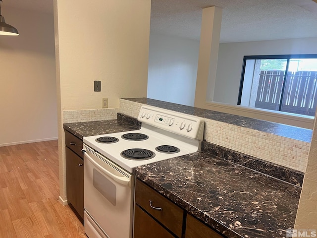 kitchen with dark brown cabinets, dark stone counters, decorative light fixtures, white electric range oven, and light hardwood / wood-style floors