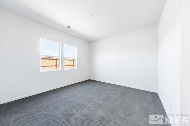 spare room featuring dark colored carpet