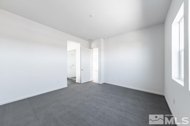 spare room featuring dark colored carpet