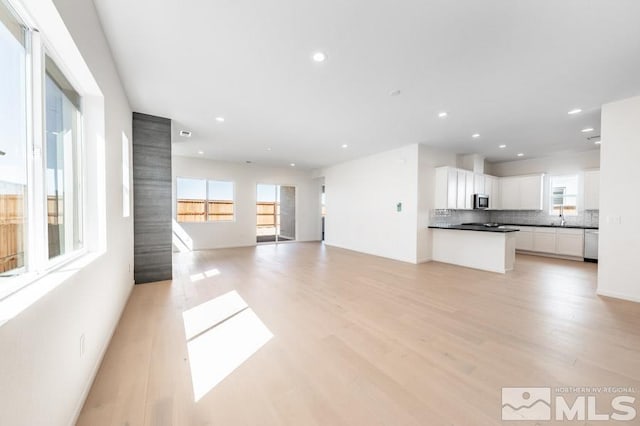 unfurnished living room with sink and light hardwood / wood-style flooring