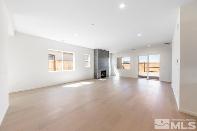 unfurnished living room with a fireplace and light wood-type flooring