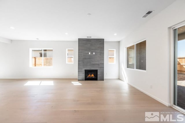 unfurnished living room featuring light hardwood / wood-style flooring and a tile fireplace