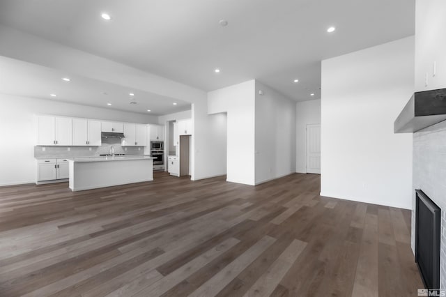 unfurnished living room with dark wood-type flooring, sink, and a fireplace