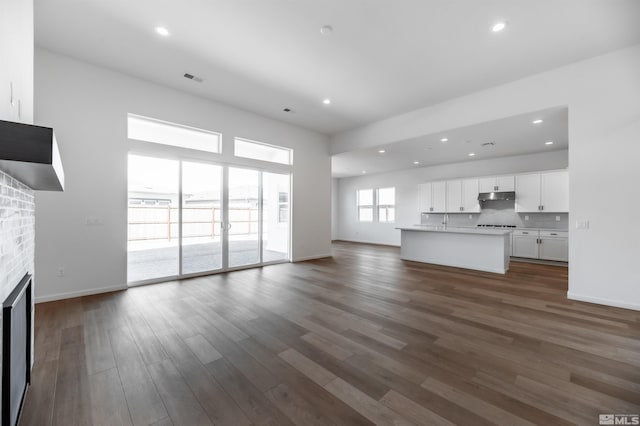 unfurnished living room featuring a brick fireplace and dark hardwood / wood-style floors