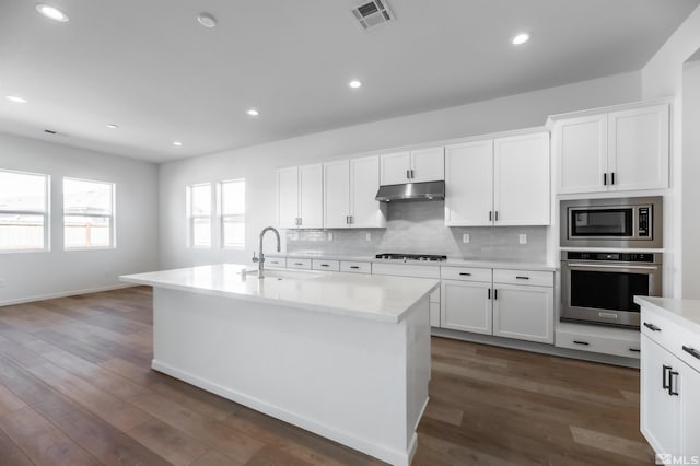 kitchen with white cabinetry, a center island with sink, dark hardwood / wood-style flooring, and appliances with stainless steel finishes