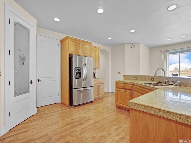 kitchen with sink, stainless steel fridge, light hardwood / wood-style floors, light brown cabinetry, and kitchen peninsula