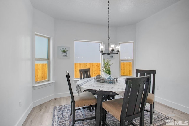 dining space featuring an inviting chandelier, a textured ceiling, and light hardwood / wood-style floors