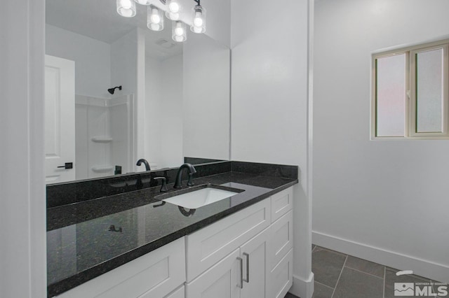 bathroom with a chandelier, vanity with extensive cabinet space, and tile flooring