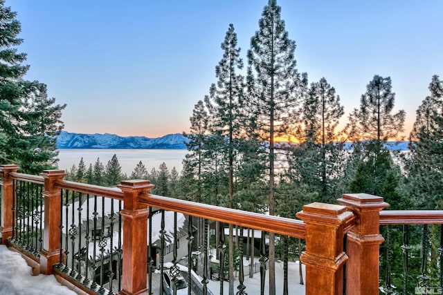 deck at dusk featuring a water and mountain view