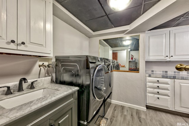 washroom with light hardwood / wood-style flooring, sink, cabinets, and washer and dryer