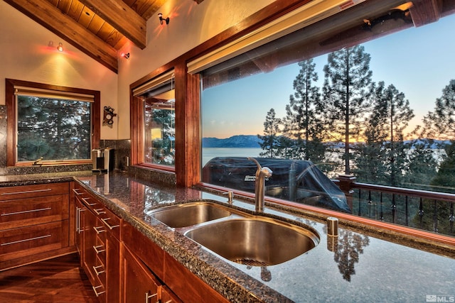 kitchen with lofted ceiling with beams, wooden ceiling, a mountain view, dark stone countertops, and sink