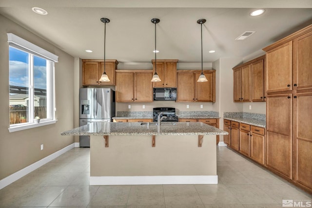 kitchen with hanging light fixtures, stainless steel fridge, light tile flooring, a kitchen breakfast bar, and a center island with sink