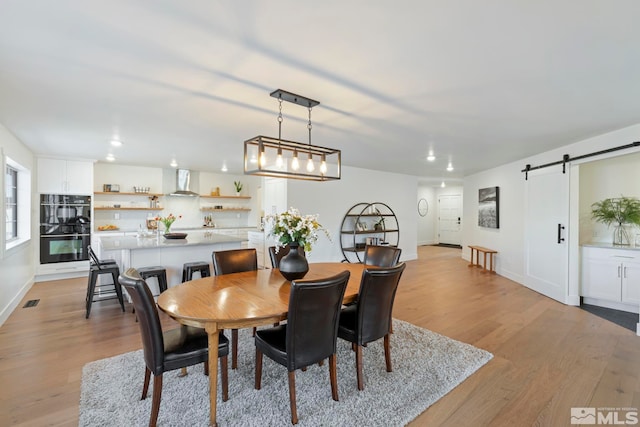 dining area with light hardwood / wood-style flooring and a barn door