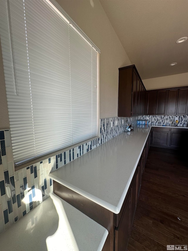 kitchen with backsplash, dark brown cabinets, and dark hardwood / wood-style floors