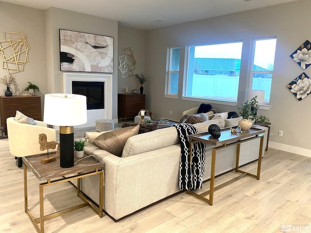 living room with a glass covered fireplace, light wood-style flooring, and baseboards