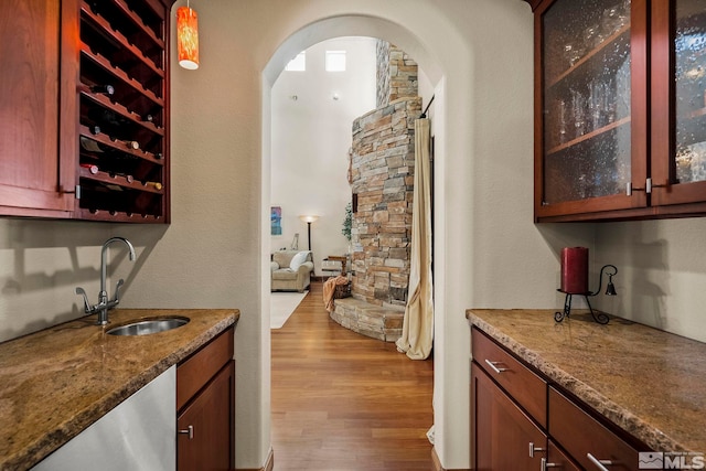 bar with stone countertops, hardwood / wood-style floors, hanging light fixtures, and sink