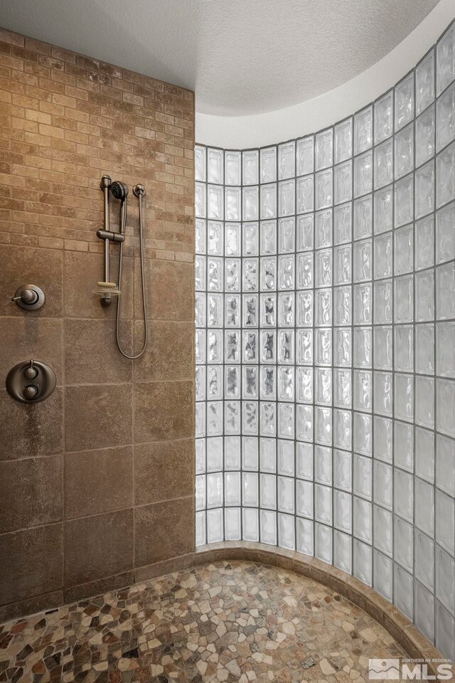 bathroom with tiled shower and a textured ceiling