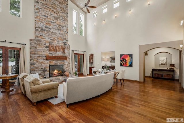 living room featuring ceiling fan, dark wood-type flooring, and a towering ceiling