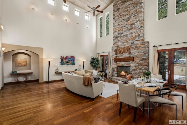 living room featuring ceiling fan, dark hardwood / wood-style floors, a fireplace, and high vaulted ceiling