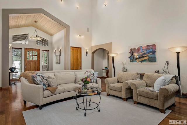 living room featuring high vaulted ceiling, dark hardwood / wood-style floors, and an inviting chandelier