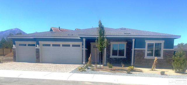 view of front of house featuring a garage, stone siding, decorative driveway, and stucco siding