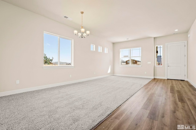 unfurnished room featuring wood-type flooring and an inviting chandelier