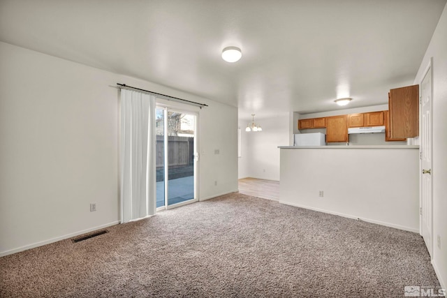 unfurnished living room featuring a chandelier and carpet flooring