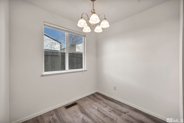 empty room featuring a notable chandelier and hardwood / wood-style floors