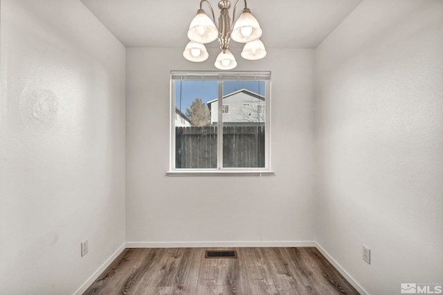 unfurnished room featuring a chandelier and hardwood / wood-style floors