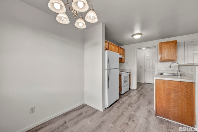 kitchen with white appliances, sink, hanging light fixtures, a notable chandelier, and light hardwood / wood-style flooring