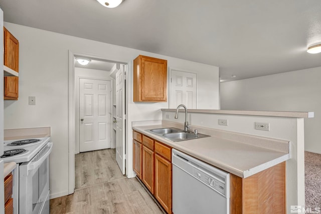 kitchen featuring light wood-type flooring, sink, kitchen peninsula, and white appliances