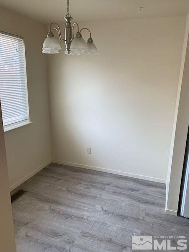 unfurnished dining area with plenty of natural light, an inviting chandelier, and light hardwood / wood-style floors