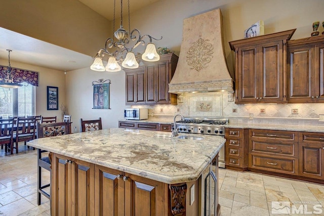 kitchen with custom range hood, a kitchen island with sink, backsplash, and light tile floors