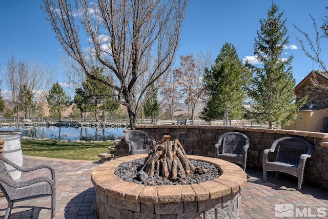 view of terrace with a fire pit and a water view