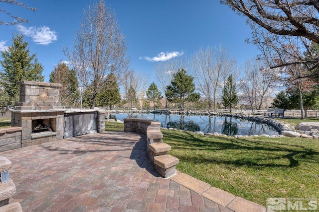 view of terrace featuring an outdoor stone fireplace and a water view