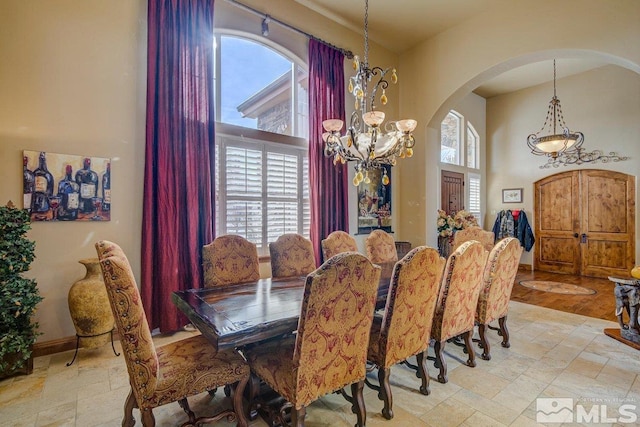 tiled dining room featuring an inviting chandelier, a high ceiling, and plenty of natural light