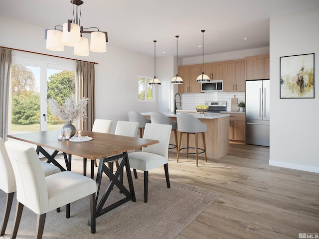 dining area featuring a chandelier, sink, and light hardwood / wood-style flooring