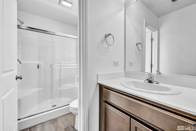 bathroom with walk in shower, wood-type flooring, toilet, and vanity