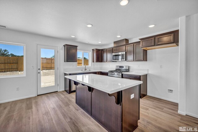 kitchen with a kitchen bar, appliances with stainless steel finishes, sink, light wood-type flooring, and a center island