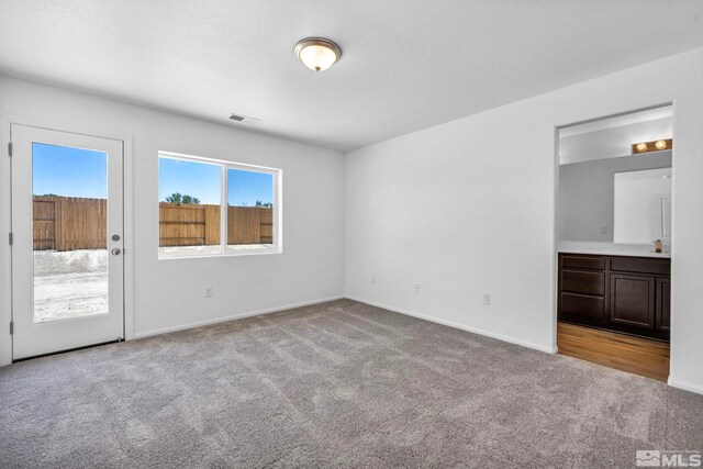 unfurnished bedroom featuring light carpet and connected bathroom