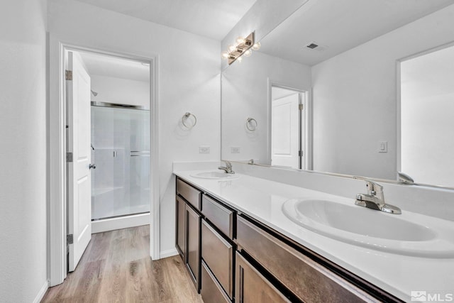 bathroom with walk in shower, double sink vanity, and hardwood / wood-style floors