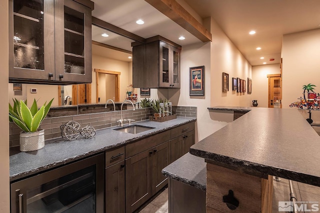 kitchen with tasteful backsplash, dark stone countertops, wine cooler, and sink