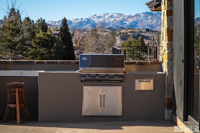 view of terrace featuring a mountain view, a grill, and exterior kitchen