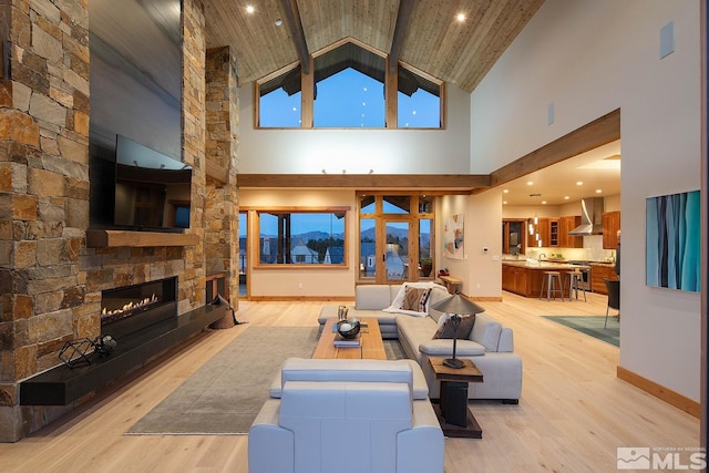 living room featuring light hardwood / wood-style flooring, a stone fireplace, high vaulted ceiling, and wooden ceiling