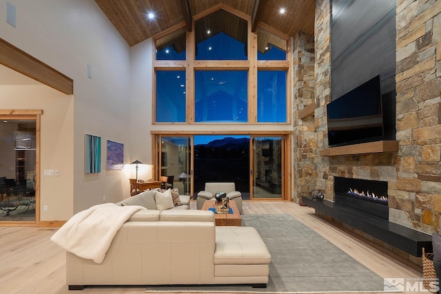 living room featuring beam ceiling, a fireplace, high vaulted ceiling, wooden ceiling, and light hardwood / wood-style flooring