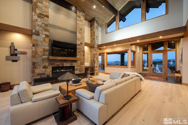 living room featuring a fireplace, high vaulted ceiling, a mountain view, light wood-type flooring, and beam ceiling