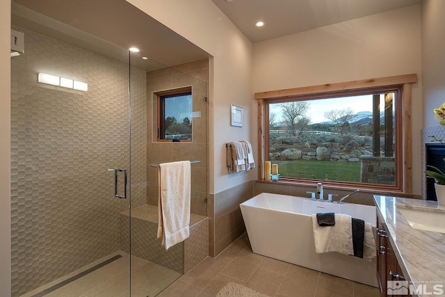 bathroom with shower with separate bathtub, a healthy amount of sunlight, tile floors, and vanity