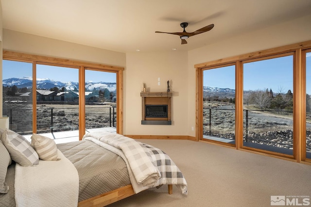 carpeted bedroom with ceiling fan, a mountain view, multiple windows, and access to outside