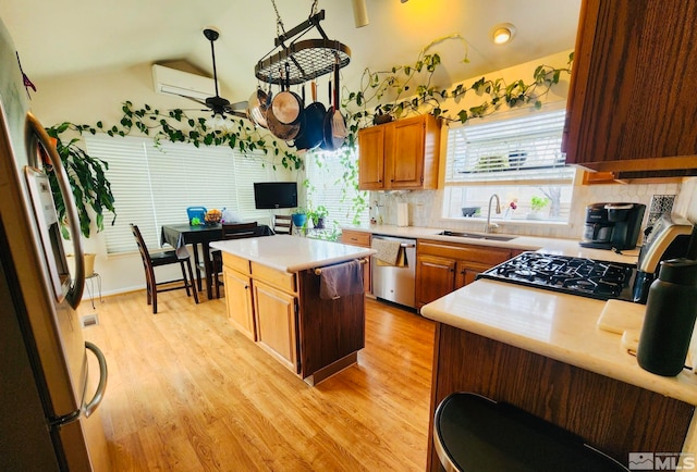 kitchen with appliances with stainless steel finishes, a center island, ceiling fan, sink, and light hardwood / wood-style flooring