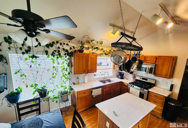 kitchen with appliances with stainless steel finishes, track lighting, ceiling fan, backsplash, and light hardwood / wood-style floors